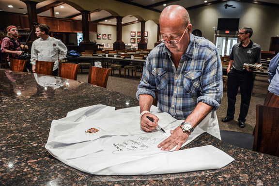 Andrew Zimmern signing a chef coat at the Certified Angus Beef® Education & Culinary Center in Wooster, OH